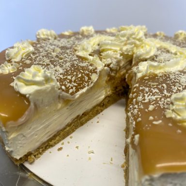 A mint cheesecake adorned with chocolate balls and chopped mint aero on top.